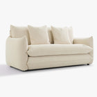 Angled front view of the Blossom sofa bed in Bisque with curved arms, back cushions and two decorative cushions.