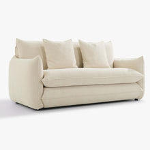 Angled front view of the Blossom sofa bed in Bisque with curved arms, back cushions and two decorative cushions.