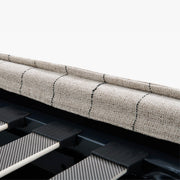 Detail of the Dormi bed’s upholstered frame edge and black mattress-support slats.