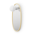 Oval shaped mirror with butter yellow frame and a portable lamp on a white background