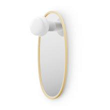 Oval shaped mirror with butter yellow frame and a portable lamp on a white background