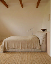 Dormi upholstered bed in Cobblestone fabric, styled with neutral bedding in a bedroom with exposed timber beams.