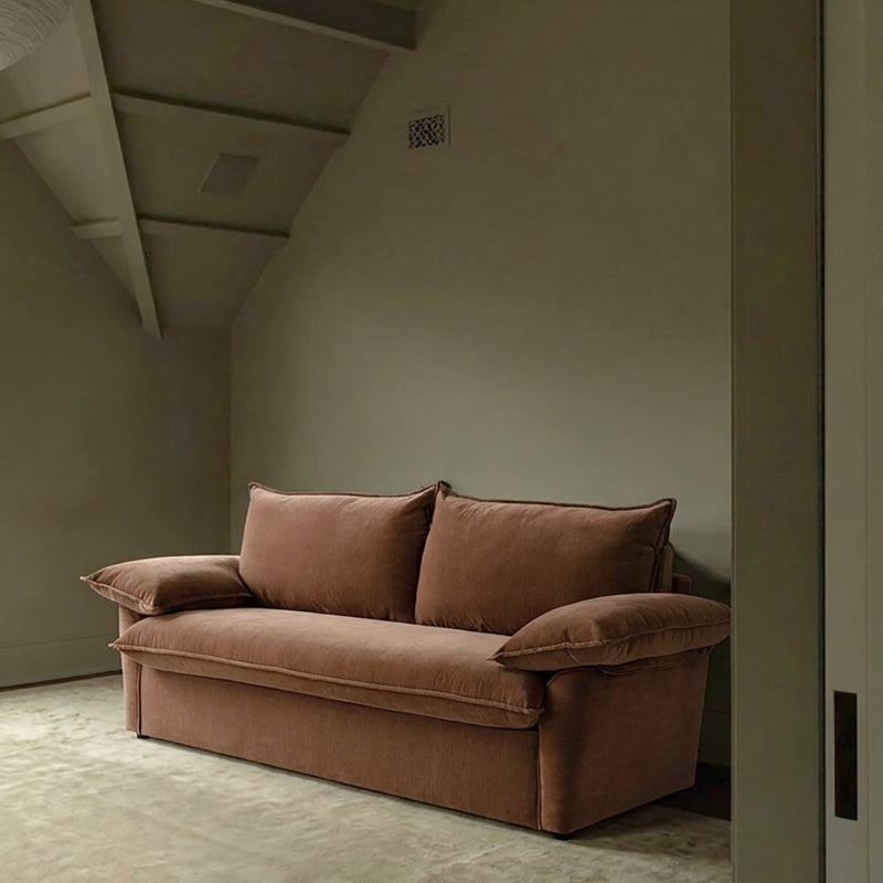 Ease sofa bed in Bronze with cushioned arms and matching back cushions, styled against a warm beige wall.
