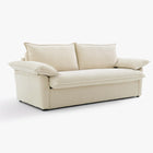 Angled front view of the Ease sofa bed in Bisque, showing its upholstered seat, two back cushions and cushioned arms.