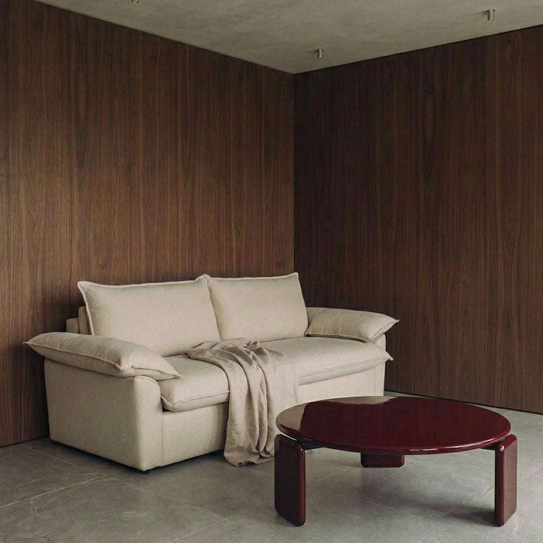 Ease sofa bed in Bisque with cushioned arms and matching back cushions, styled with a burgundy Ponte coffee table in a wood-panelled living room.