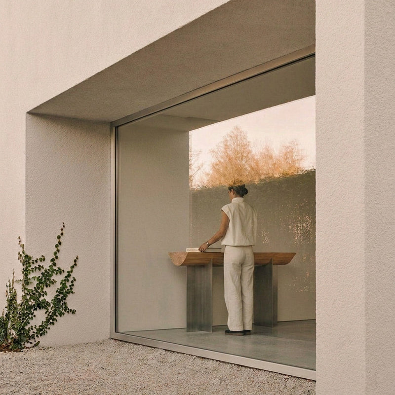 Forma Atelier console table beside a full-height window, with a person arranging objects on its Douglas fir top.