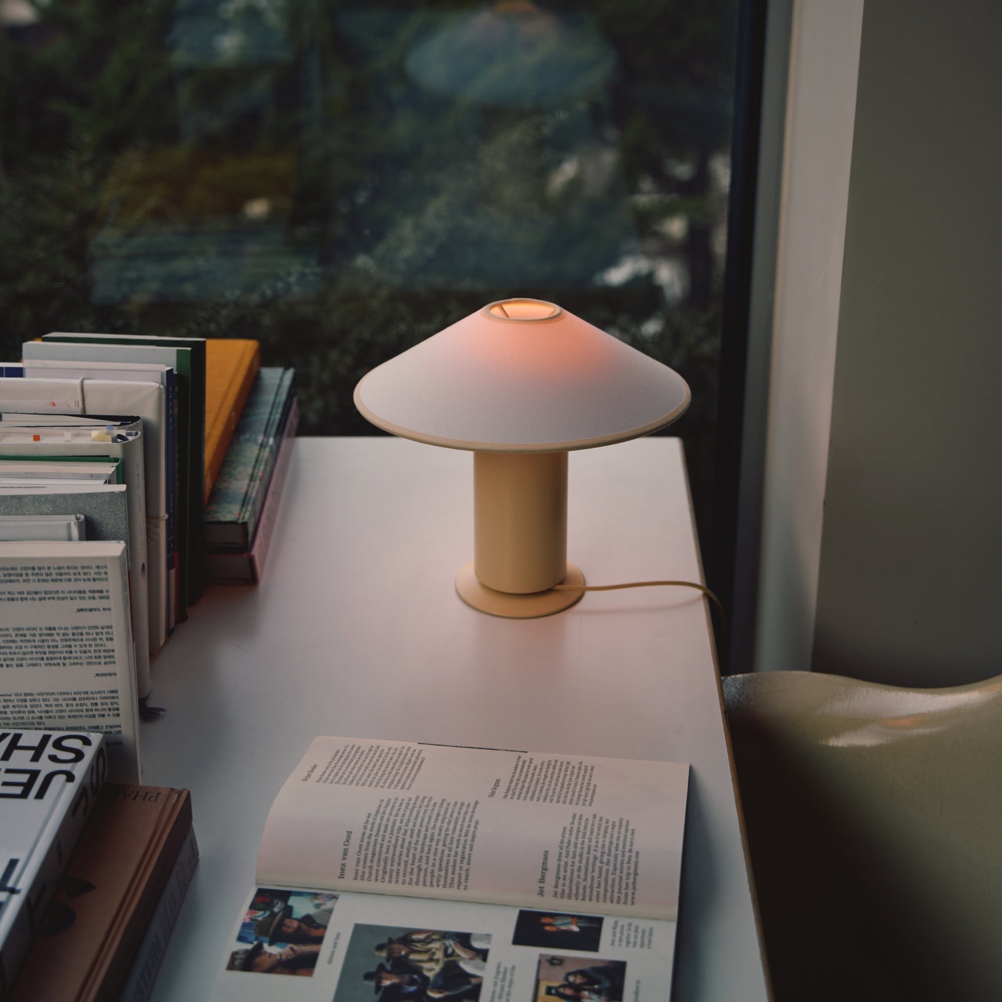 Table lamp on a surface with books and an open magazine