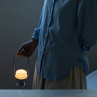 Person holding a lit lantern against a dark background
