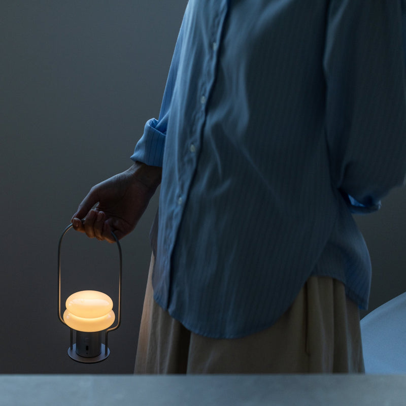 Person holding a lit lantern against a dark background
