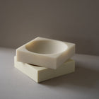 Two resin bowls stacked on a grey surface with a dark background