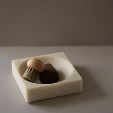 Resin bowl with a wooden brush and brown object on a gray surface