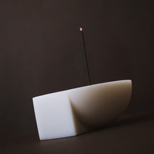 Resin incense holder with a single incense stick on a dark background