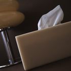 Resin tissue box cover with a tissue peeking out on a dark surface