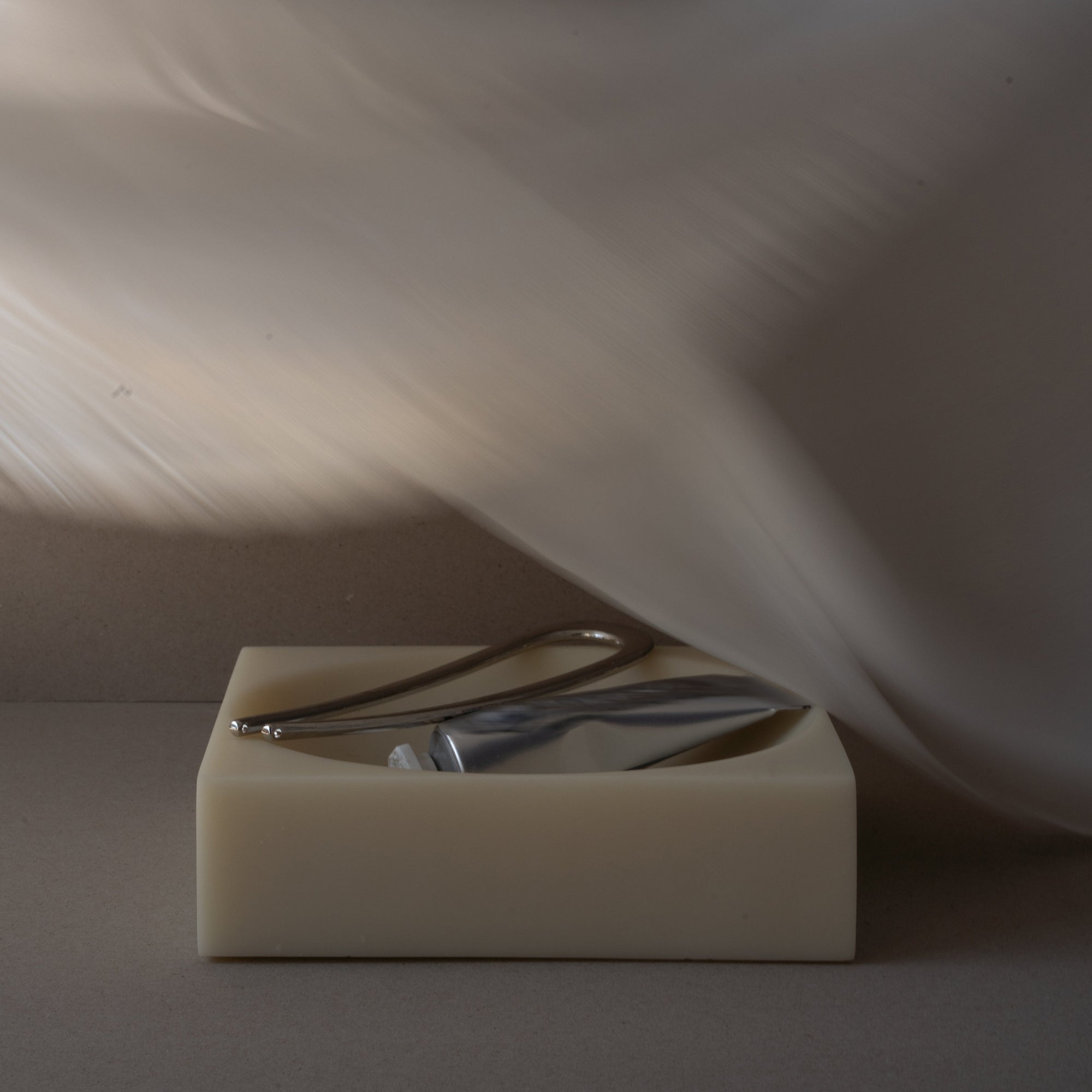 Small resin bowl with a hair pin and skincare tube on a white background