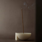 Incense stick burning in a incense holder against a dark background