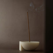 Burning incense stick in a LUME resin incense bowl against a dark background