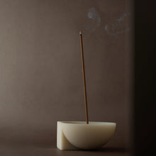 Incense stick burning in a incense holder against a dark background