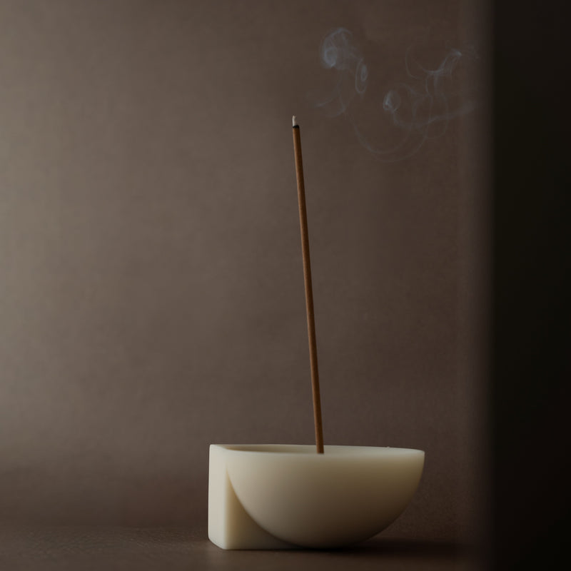 Incense stick burning in a incense holder against a dark background
