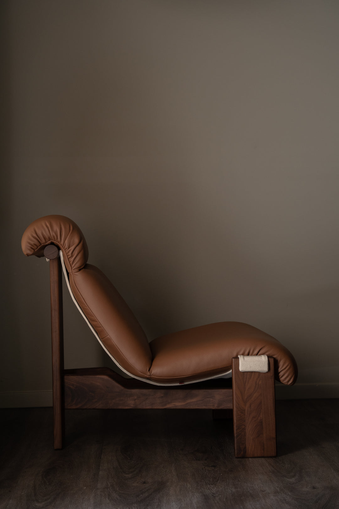 Brown leather lounge chair against a plain wall