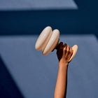 Hand holding a butter and white coloured portable table lamp against a blue background
