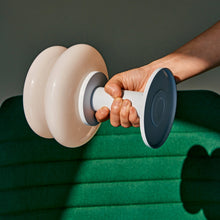 Hand holding a white and pale blue portable lamp on a green surface