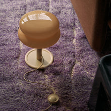 Butter coloured lamp with a butter shade on a purple textured rug