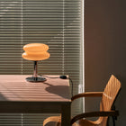 Table lamp on a table with a chair and blinds in the background