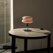 Peach coloured shade table lamp on a round table with a dark background