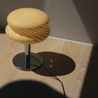 Table lamp with a swirling design on the lamp shade on a wooden surface