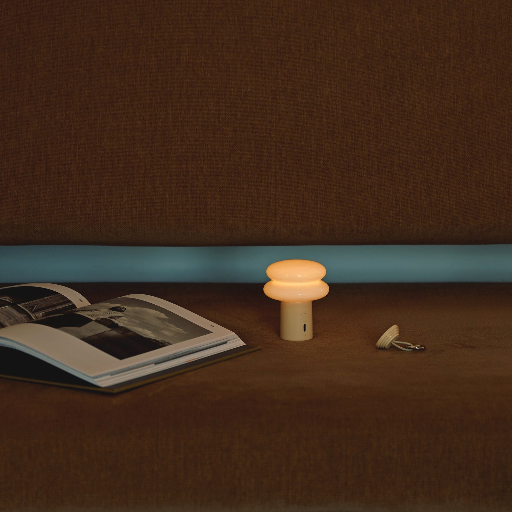 Small lamp on a table next to an open book with a dark brown background