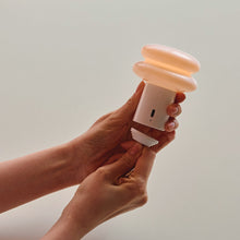 Person holding a lamp and the carabiner key chain in front of a neutral background
