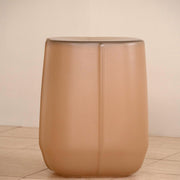 Front view of the VETRO glass side table in Sable on a pale tiled floor, showing its rounded base and vertical ridge.