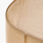Close-up of the VETRO side table in Sable, showing the textured glass tabletop, rounded edge and warm sandy tones.