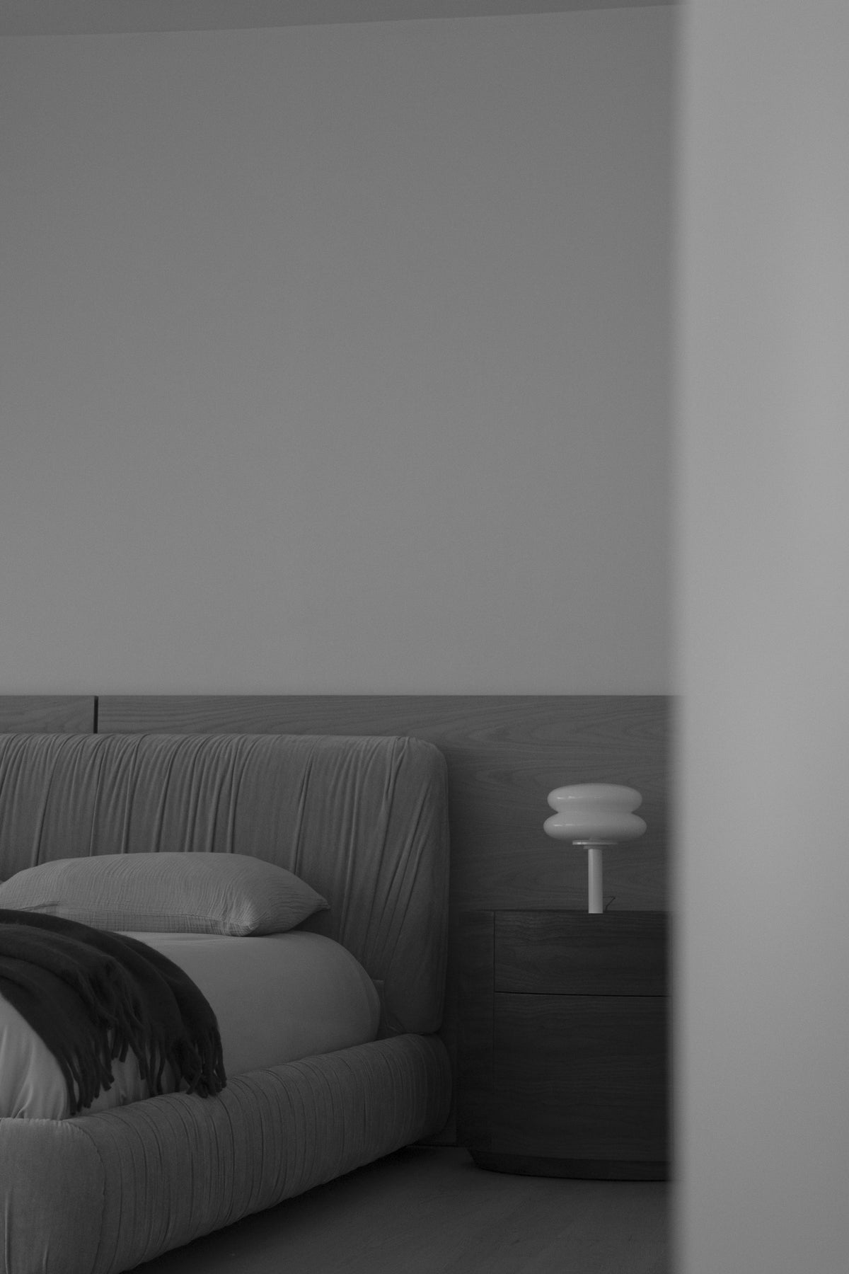 Trovato Penthouse bedroom with an upholstered bed, timber bedside table and sculptural lamp